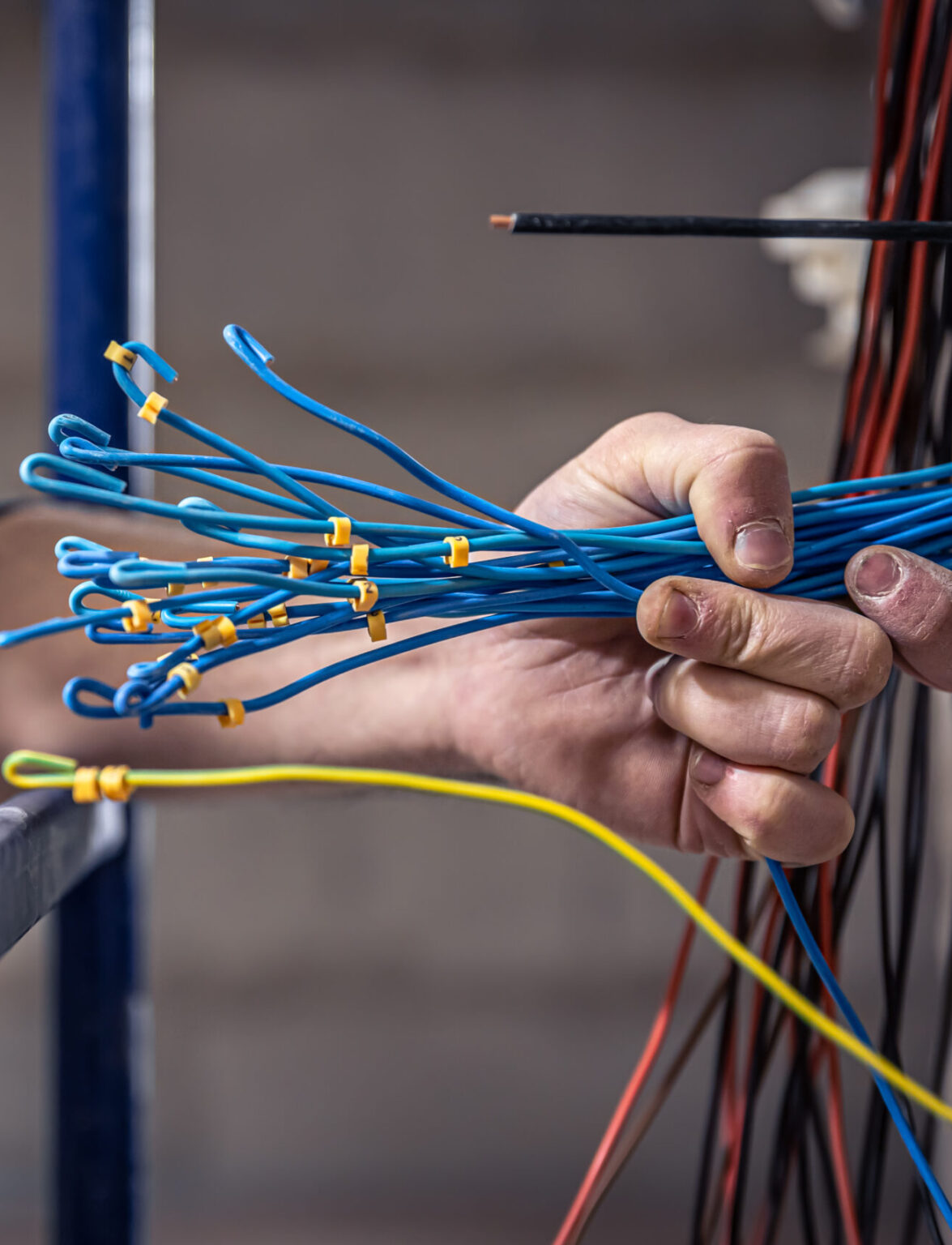 A construction electrician cuts a voltage cable during a repair, close up.